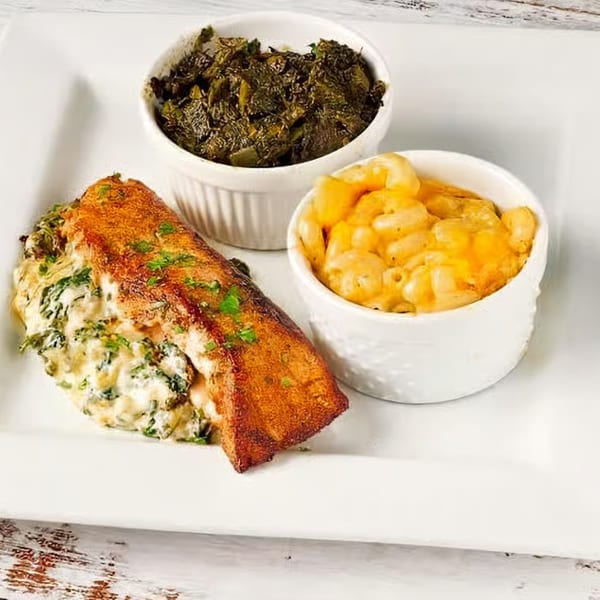 Soul Vibez's fried salmon with creamy spinach, mac and cheese, and collard greens on a white plate.
