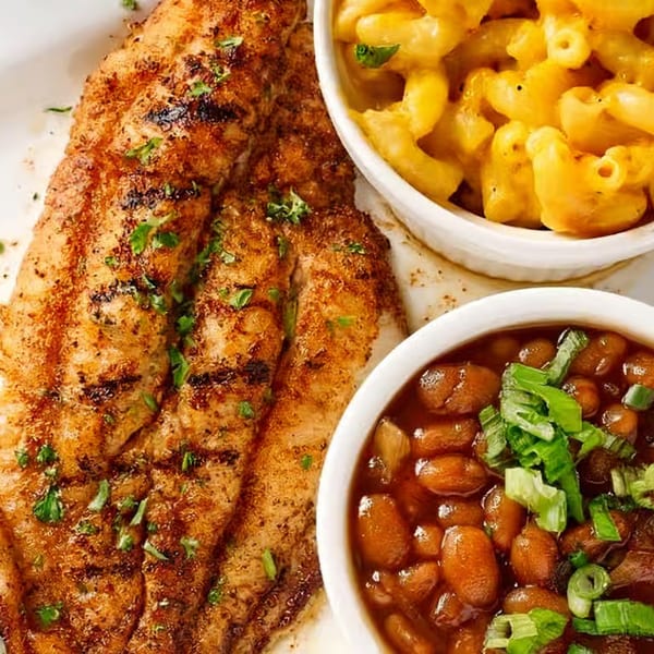 Soul Vibez's grilled fish fillet with mac and cheese and baked beans, garnished with parsley and scallions.
